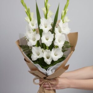 Fresh white gladiolus bouquet in brown paper wrapping by Gull Flowers.